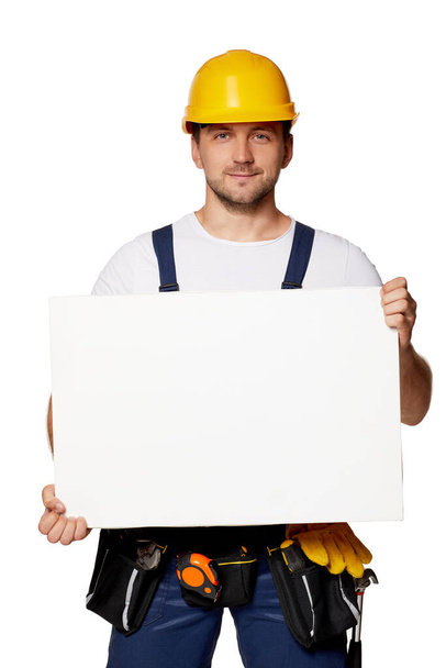 repairman in uniform holding empty blank board. - 写真・画像