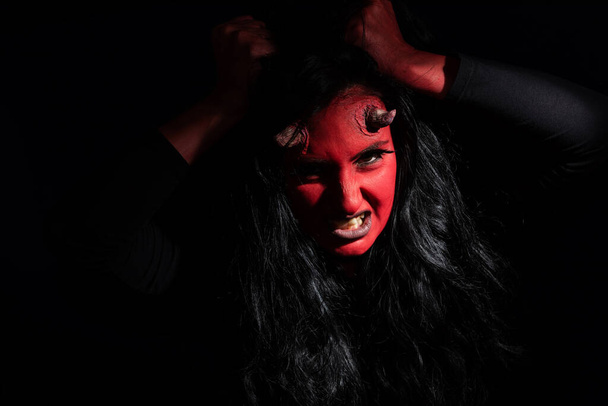 Halloween concept. Demon woman with red face and small horns on black background with copy space. Ideas for halloween body art - Foto, immagini