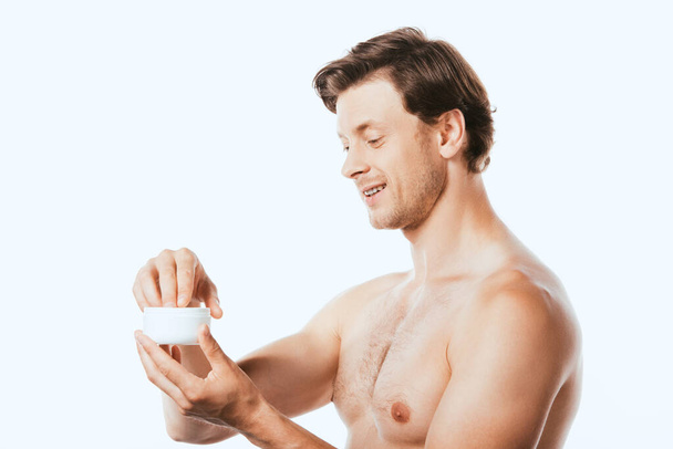 Homme torse nu tenant un bocal de crème cosmétique isolé sur blanc - Photo, image
