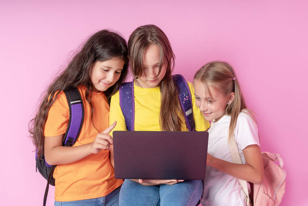 Три школярки дивляться на ноутбук з ентузіазмом. Концепція дистанційного навчання
. - Фото, зображення