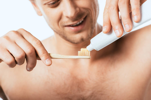 Cropped view of shirtless man holding toothbrush and toothpaste isolated on white - Fotó, kép