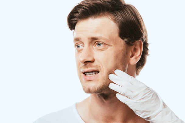 Dermatologue en gant de latex touchant la joue du patient isolé sur blanc - Photo, image