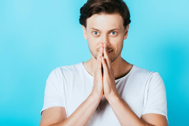 Man showing please gesture while looking at camera on blue background - Fotó, kép