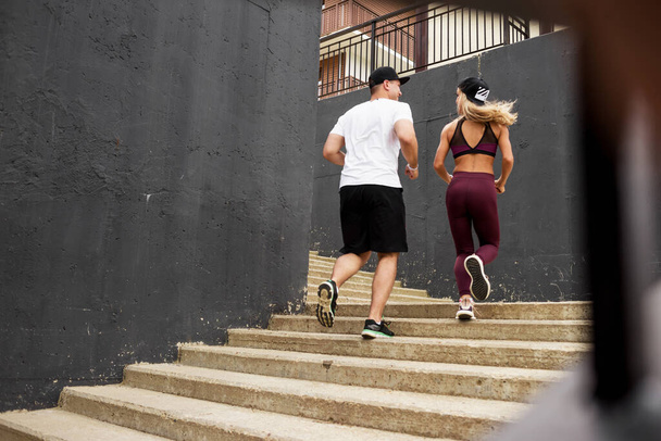fitness, sport, people, exercising and lifestyle concept - couple running upstairs on city stairs - Foto, afbeelding
