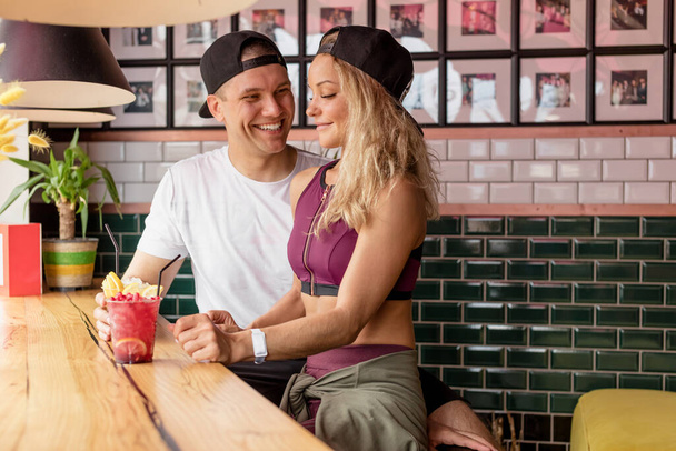 Sportive couple sitting in a cafe enjoying fresh drinks after intensive workout. - Zdjęcie, obraz