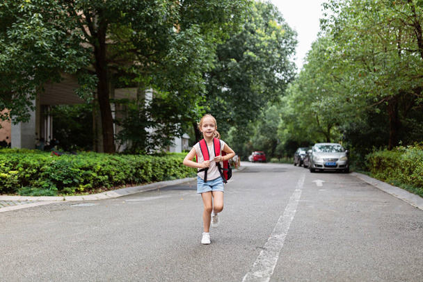 School child after end coronavirus pandemic outbreak. Blonde girl going back to school after covid-19 quarantine and lockdown. Happy kid outdoor. New normal. High quality photo - Фото, изображение