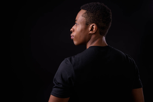 Studio shot of young handsome African man against black background - Photo, Image