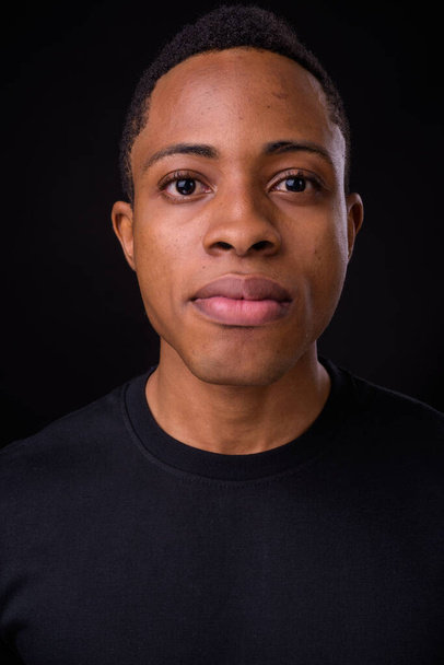 Studio shot of young handsome African man against black background - Photo, Image