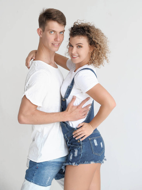 счастливая пара, обнимающая джинсовую одежду на белом фоне. подлинная пара, развлекающаяся в помещении. - Фото, изображение