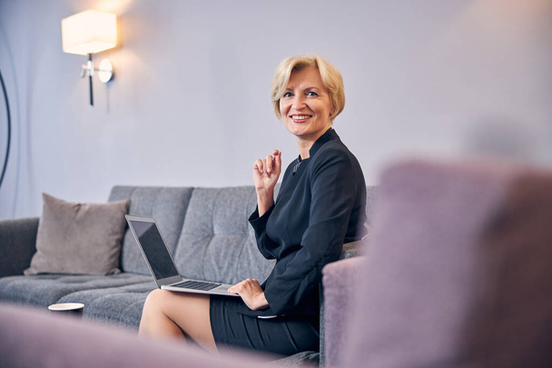 Cheerful businesswoman using laptop in hotel room - Fotoğraf, Görsel