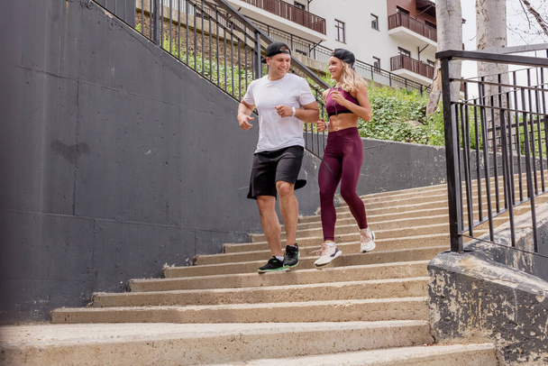 Couple running on stairs in morning, jogging in urban area with starecases. - Photo, image