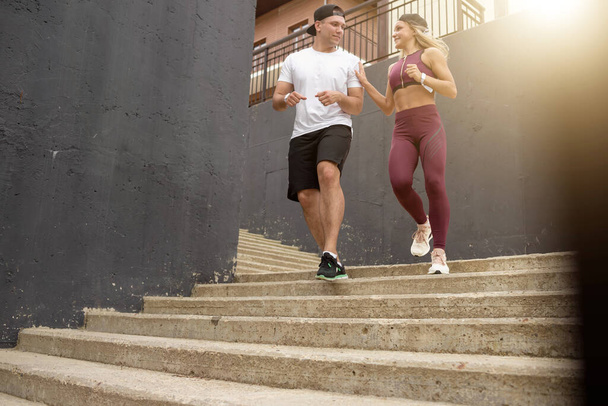 Couple running on stairs in morning, jogging in urban area with starecases. - Φωτογραφία, εικόνα