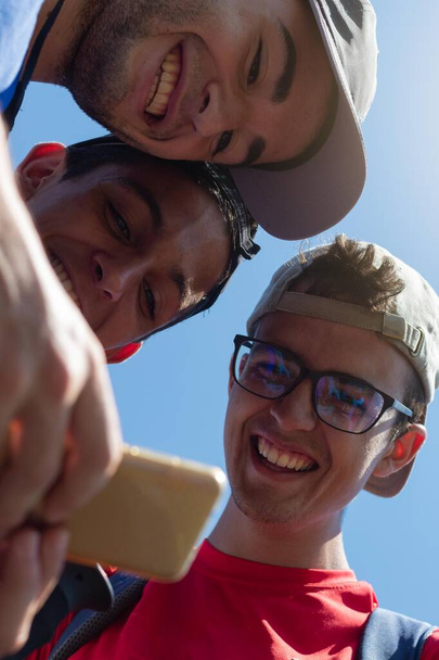 jóvenes sonriendo mirando fotos y redes sociales móviles durante una larga caminata por el Camino de Santiago en España en un día de verano - Foto, Imagen