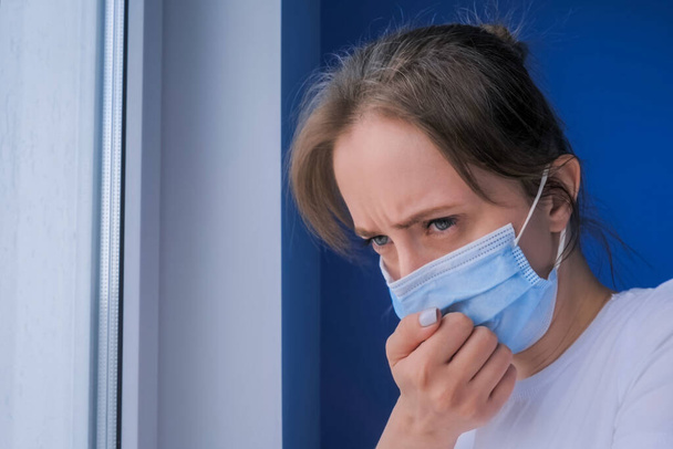 mujer con mascarilla que sufre de tos, mirando por la ventana - de cerca - Foto, imagen