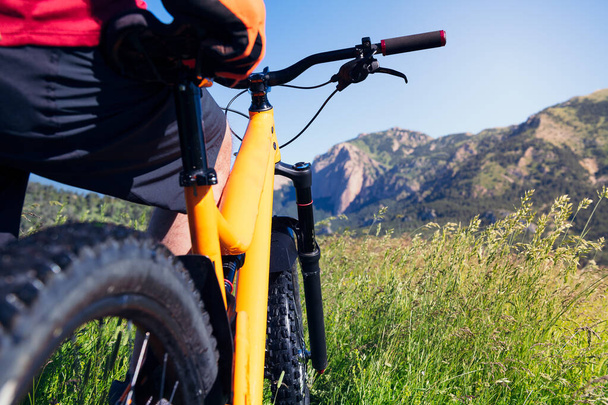 κοντινό πλάνο ενός άνδρα που παρατηρεί το τοπίο και τα βουνά που στέκονται δίπλα στο ποδήλατο βουνού του στην ύπαιθρο, την έννοια του αθλητισμού και του υγιεινού τρόπου ζωής στη φύση, αντίγραφο χώρο για κείμενο - Φωτογραφία, εικόνα