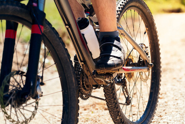close up of the wheels of a mountain bike on a dirt road, concept of sport and healthy lifestyle in nature - Foto, Bild
