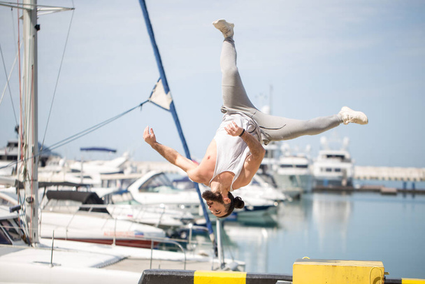 Fitness athlete doing jump squats on makeshift plyo-box on summer sea pier - Photo, Image