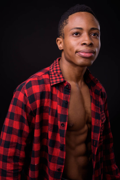 Studio záběr mladý pohledný africký hipster muž proti černé pozadí - Fotografie, Obrázek