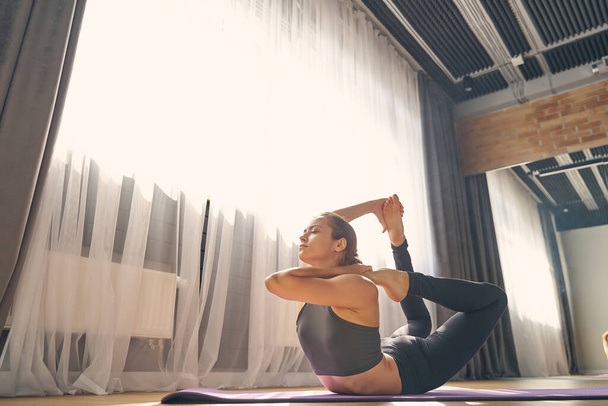 Beautiful serene woman practicing yoga in studio - Foto, afbeelding