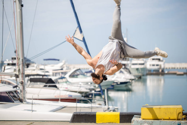Fitness athlete doing jump squats on makeshift plyo-box on summer sea pier - Фото, изображение