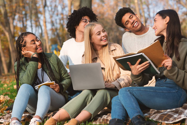 Grupa przyjaciół studentów studiujących w jesiennym parku - Zdjęcie, obraz