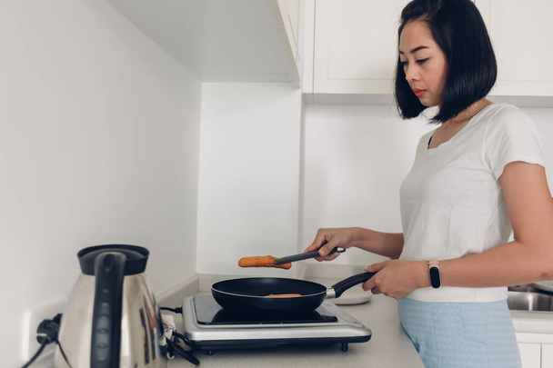 Woman is cooking simple breakfast in white cozy kitchen. - Foto, Imagen