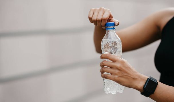 Saciar a sede. Africano americano jovem mulher com relógio inteligente abre garrafa de água
 - Foto, Imagem