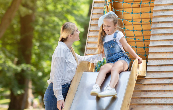 Little Girl Riding Slide Playing With Babysitter On Playground Outdoor - Photo, Image