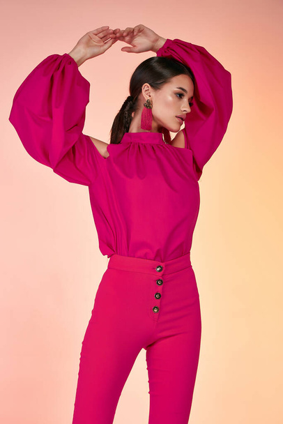 Pretty beautiful sexy elegance woman fashion model glamor pose wear red color trousers silk blouse clothes for party summer collection makeup hair style brunette success accessory bag jewelry studio. - Zdjęcie, obraz