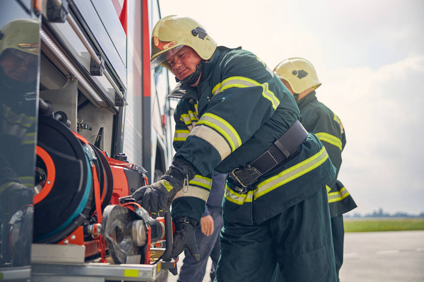 Firefighter installing equipment on the fire machine - Foto, Bild