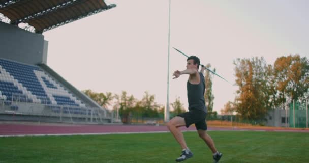 Powolny ruch: Mężczyzna atleta na stadionie koncentruje biegnie w górę i rzuca oszczepem. Przygotowania do igrzysk olimpijskich wokół - Materiał filmowy, wideo