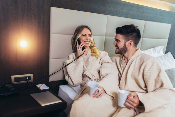 Couple calling room service for food from hotel room - Photo, Image