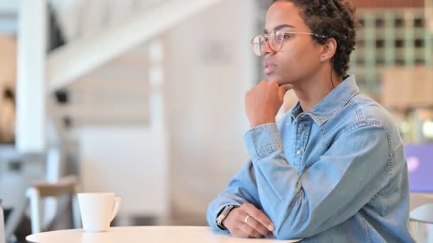 Mujer africana preocupada sentada en el café y pensando  - Metraje, vídeo