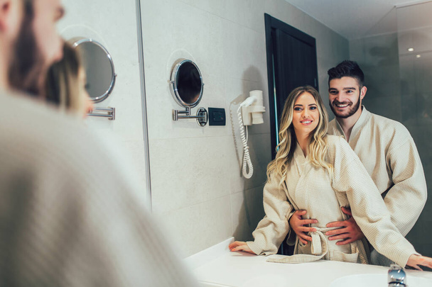 Charmant couple devant le miroir tout en se préparant dans la salle de bain - Photo, image