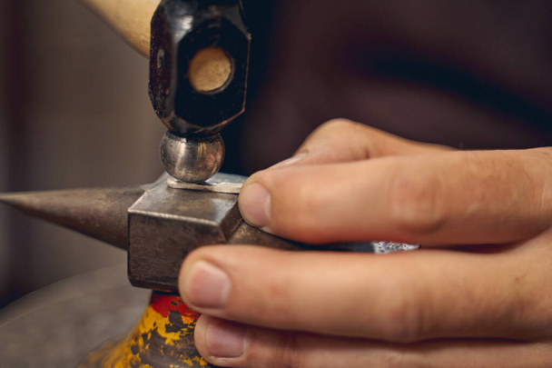 Professional Caucasian artisan using a metalsmithing tool - Fotó, kép