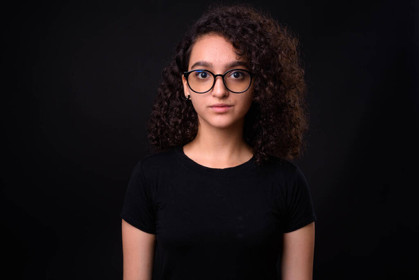 Stúdió lövés fiatal gyönyörű iráni tizenéves lány göndör haj ellen fekete háttér - Fotó, kép