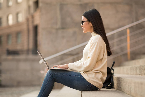 Student w okularach za pomocą laptopa, siedzi na schodach - Zdjęcie, obraz
