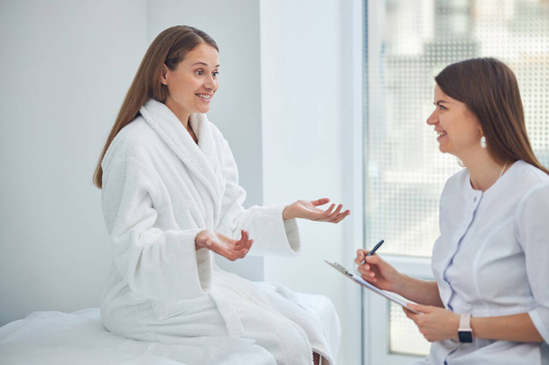 Dos mujeres sonrientes conversando en la sala de medicina blanca - Foto, imagen