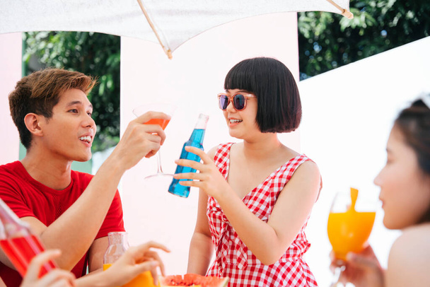 Троє азіатських людей насолоджуються напоями на літній вечірці на відкритому повітрі
. - Фото, зображення