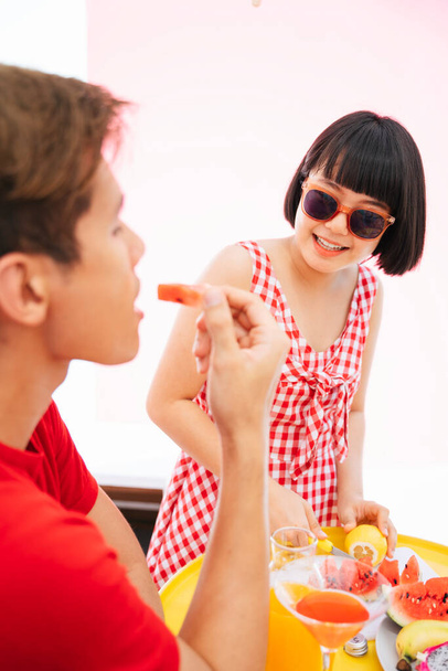 Bob účes asijské žena na červené košili nosí sluneční brýle řezání citron s nožem. Prapying fruits to serve everyone in the party. - Fotografie, Obrázek