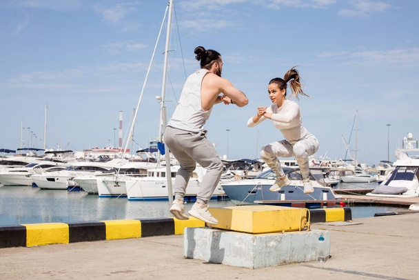 Female and male athlete is performing box jumps outdoor. - Fotografie, Obrázek