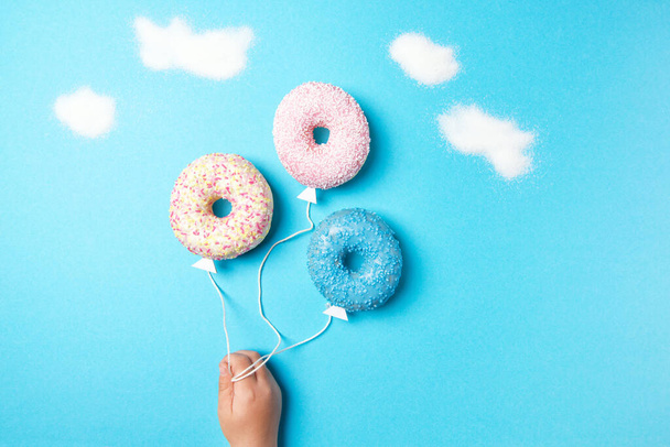 Bunte Donuts auf blauem Hintergrund, kreativer Food-Minimalismus, Donuts in Ballonform am Himmel mit Wolken aus Zucker, Draufsicht - Foto, Bild