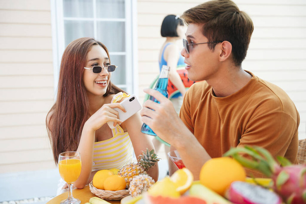 Couple asian people enjoy drinking beverage together at tropical bar. Sweet time in summer vacation. - Photo, Image