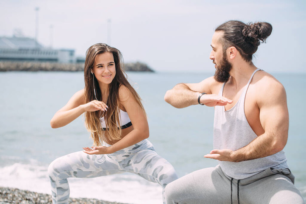 Couple warming out outdoors, doing squats together - Foto, Bild