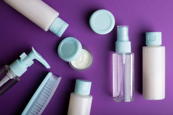 travel beauty kit on a purple background. shampoo, balm, cream and lotion in vial - Photo, Image