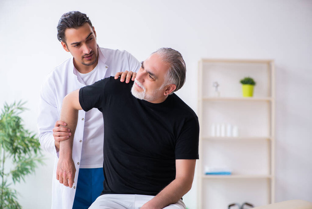 Old injured man visiting young doctor - Photo, Image