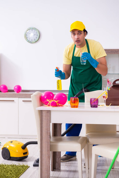Jonge mannelijke aannemer doet huishoudelijk werk na partij - Foto, afbeelding