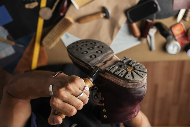Close up of shoe maker hands producing boots in his leather workshop - Foto, Imagem