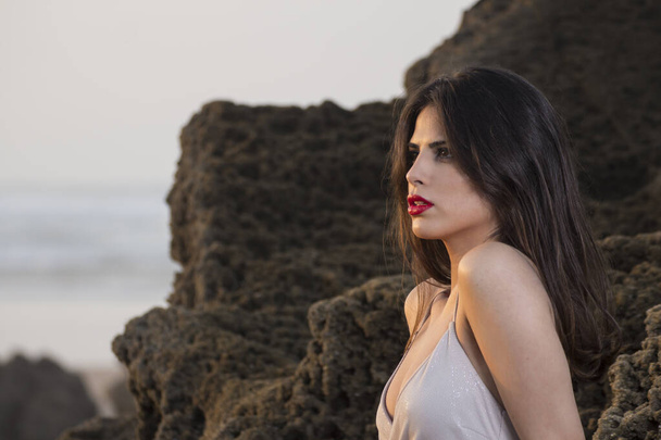 Jovem modelo feminino caucasiano nas rochas da praia
 - Foto, Imagem