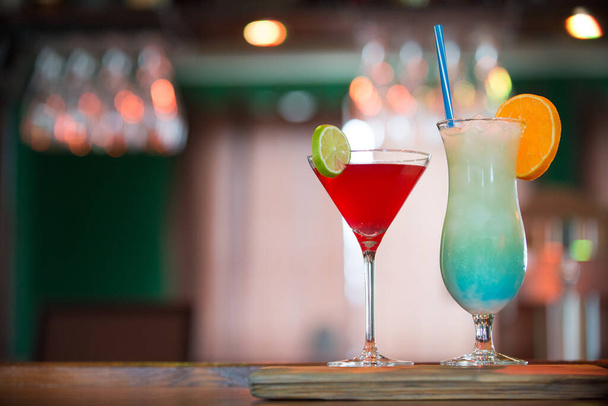 Cócteles cosmopolitas y azules hawaianos en el mostrador del bar, bebidas azules y rojas decoradas con naranja y lima en el pub - Foto, imagen